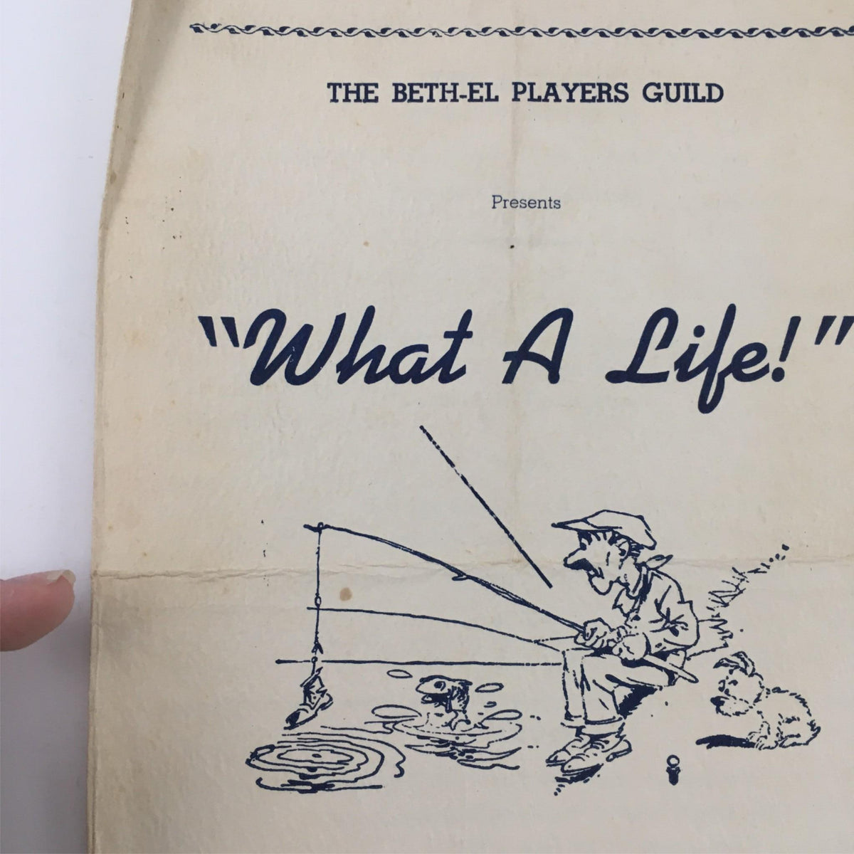 Close-up of the program cover for '1939 What A Life' presented by The Beth-El Players Guild showing a fisherman with a fishing rod.