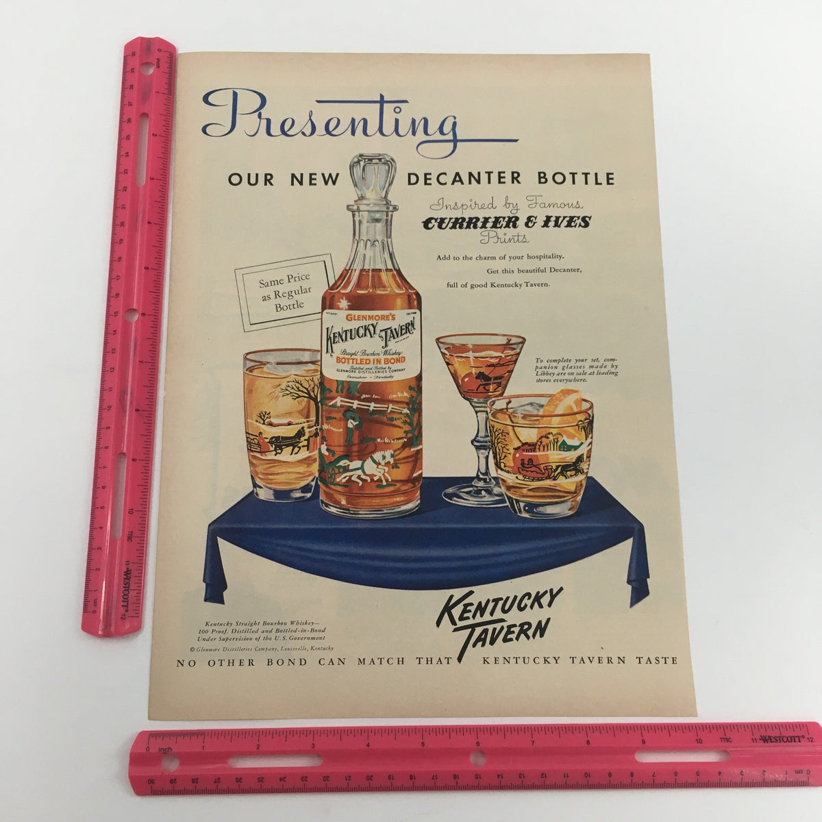 Detailed view of the 1950 Glenmore's Kentucky Tavern Straight Bourbon Whiskey Vintage Print Ad, focusing on the decanter bottle and decorative glasses with measurement ruler for scale.