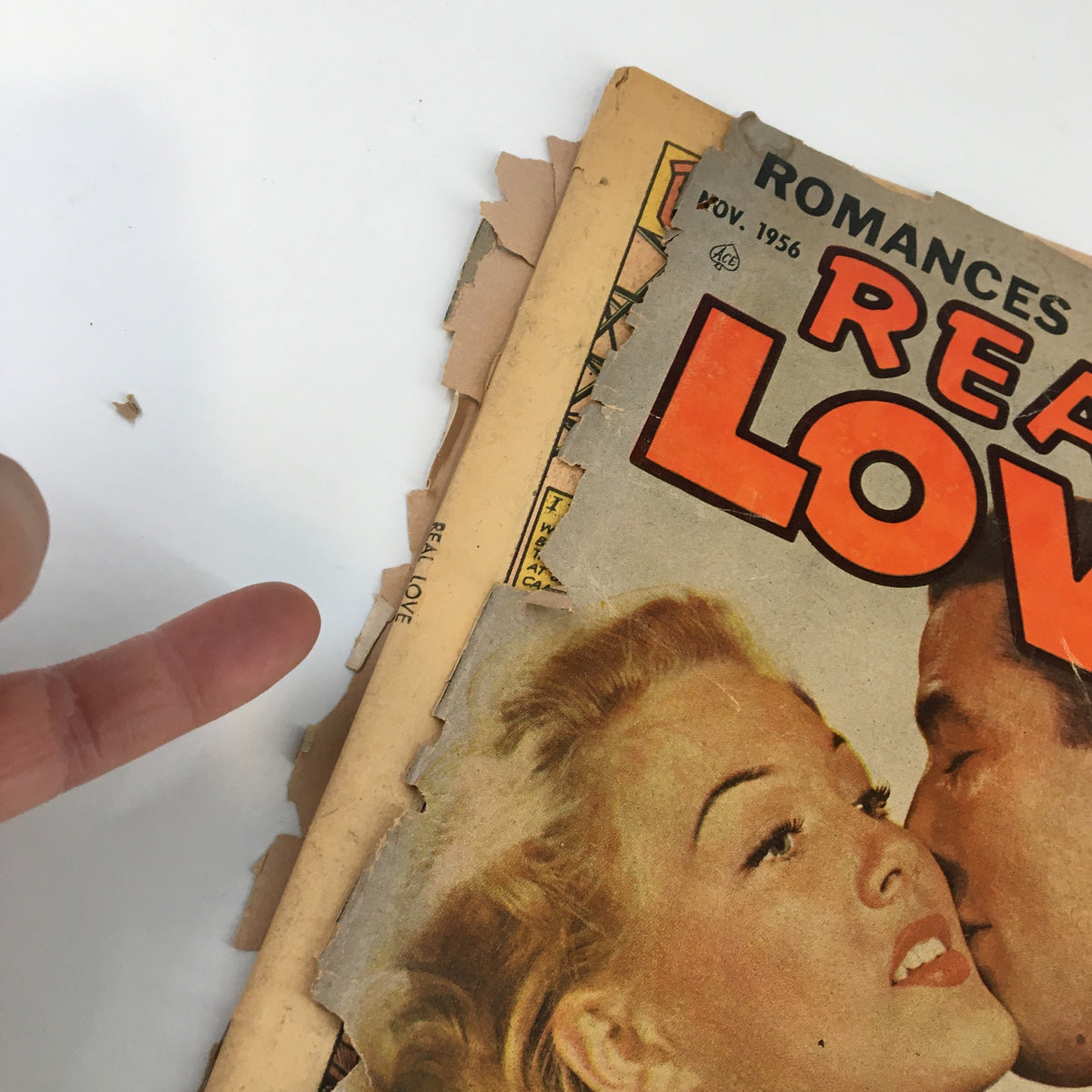 Close-up detail of the cover of VTG Real Love Magazine November 1956 showing the title 'REAL LOVE' and a glimpse of the magazine's wear and tear.