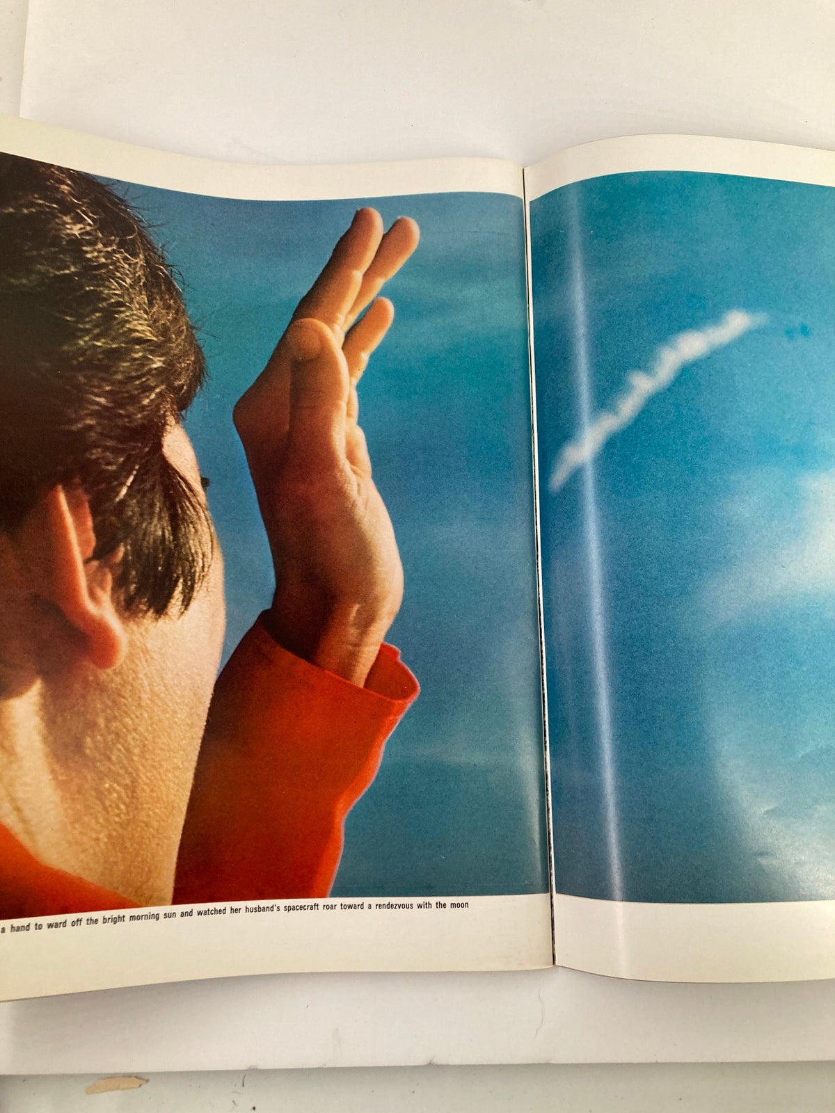Image from VTG Life Magazine 1969 To The Moon and Back showing a hand shielding the eyes, pointing toward the sky with a jet trail visible, symbolizing space exploration.