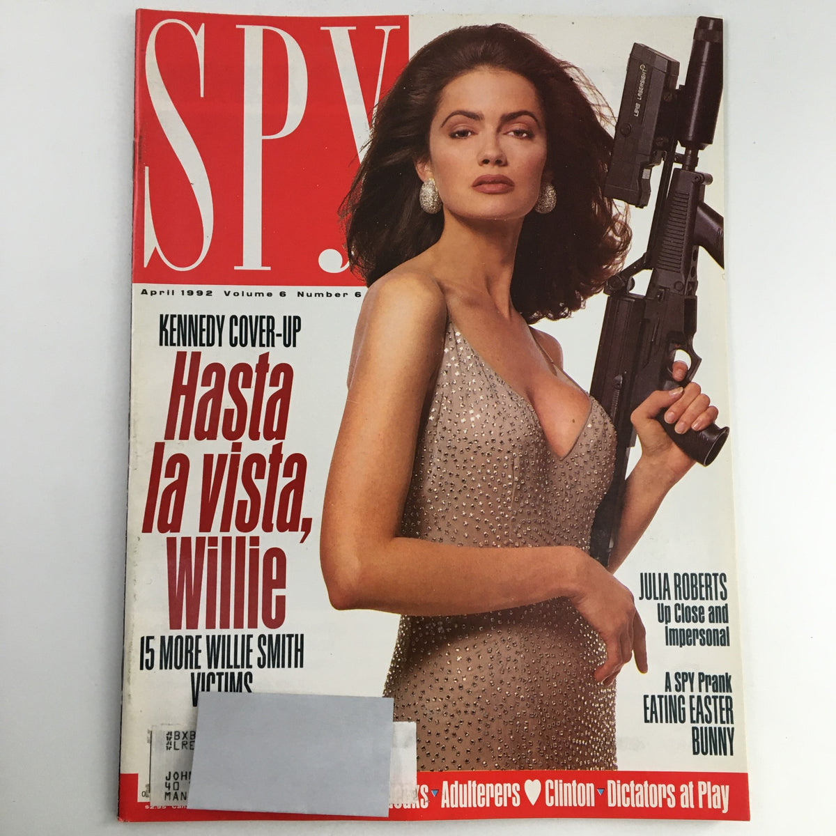 Cover of Spy Magazine from April 1992 featuring the title 'Spy Magazine April 1992 Julia Roberts & Bill Clinton & John F. Kennedy'. The cover shows a woman holding a firearm, dressed in a glamorous silver gown, with bold headlines including 'Kennedy Cover-Up' and 'Hasta la vista, Willie'.