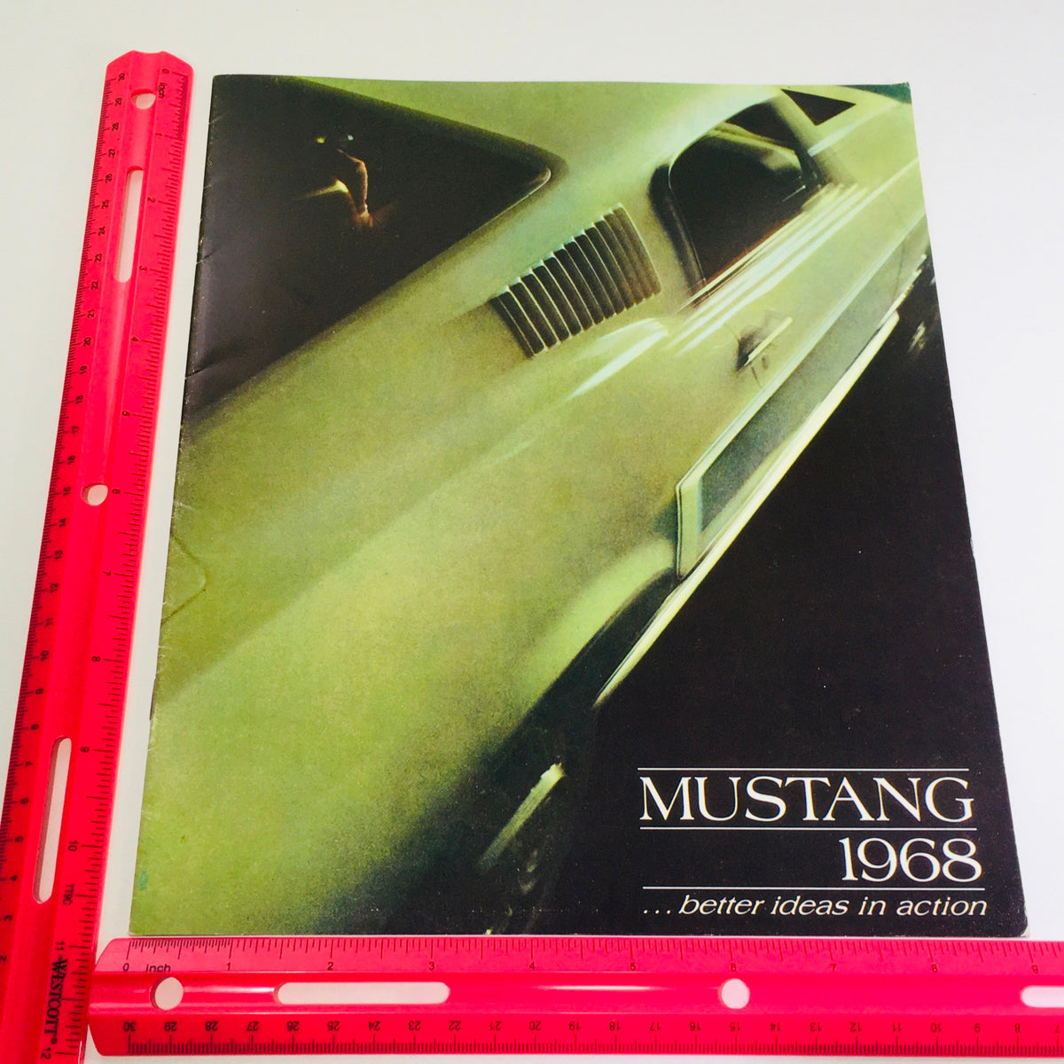 Image of the 1968 Ford Mustang ORIGINAL Sales Brochure with a ruler for scale, showcasing the brochure's cover design and title 'Mustang 1968 ... better ideas in action'.