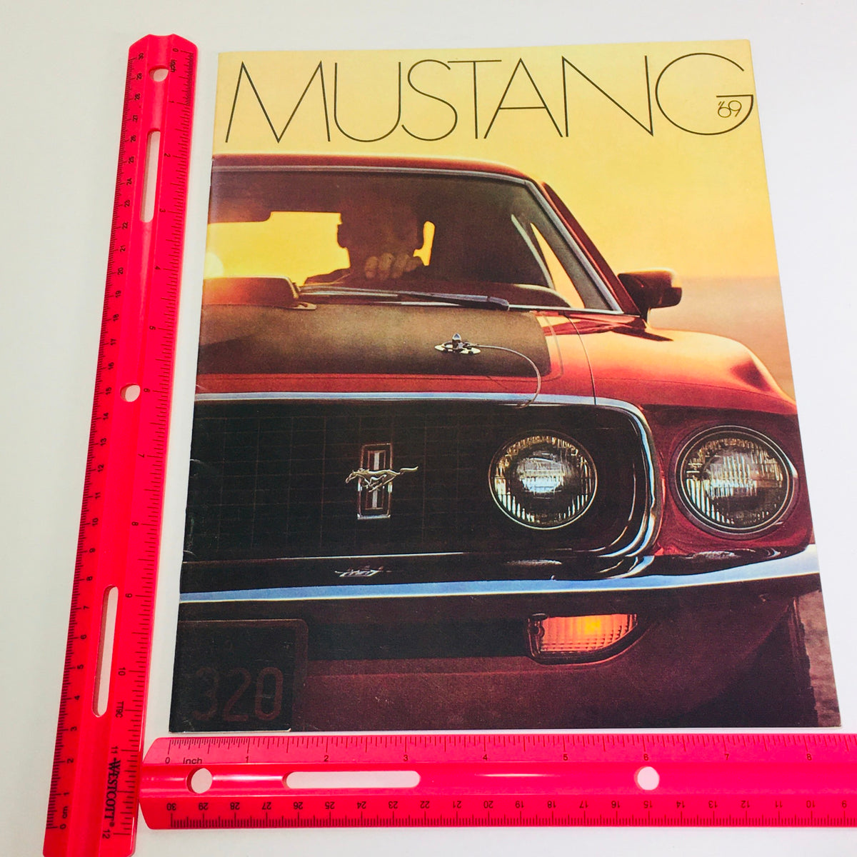 Vtg 1969 Ford Mustang Mach Hardtop Sedan 428 4-V Cobra Engine Auto Car Brochure with a ruler for scale, emphasizing the brochure's dimensions and detailed imagery of the car.