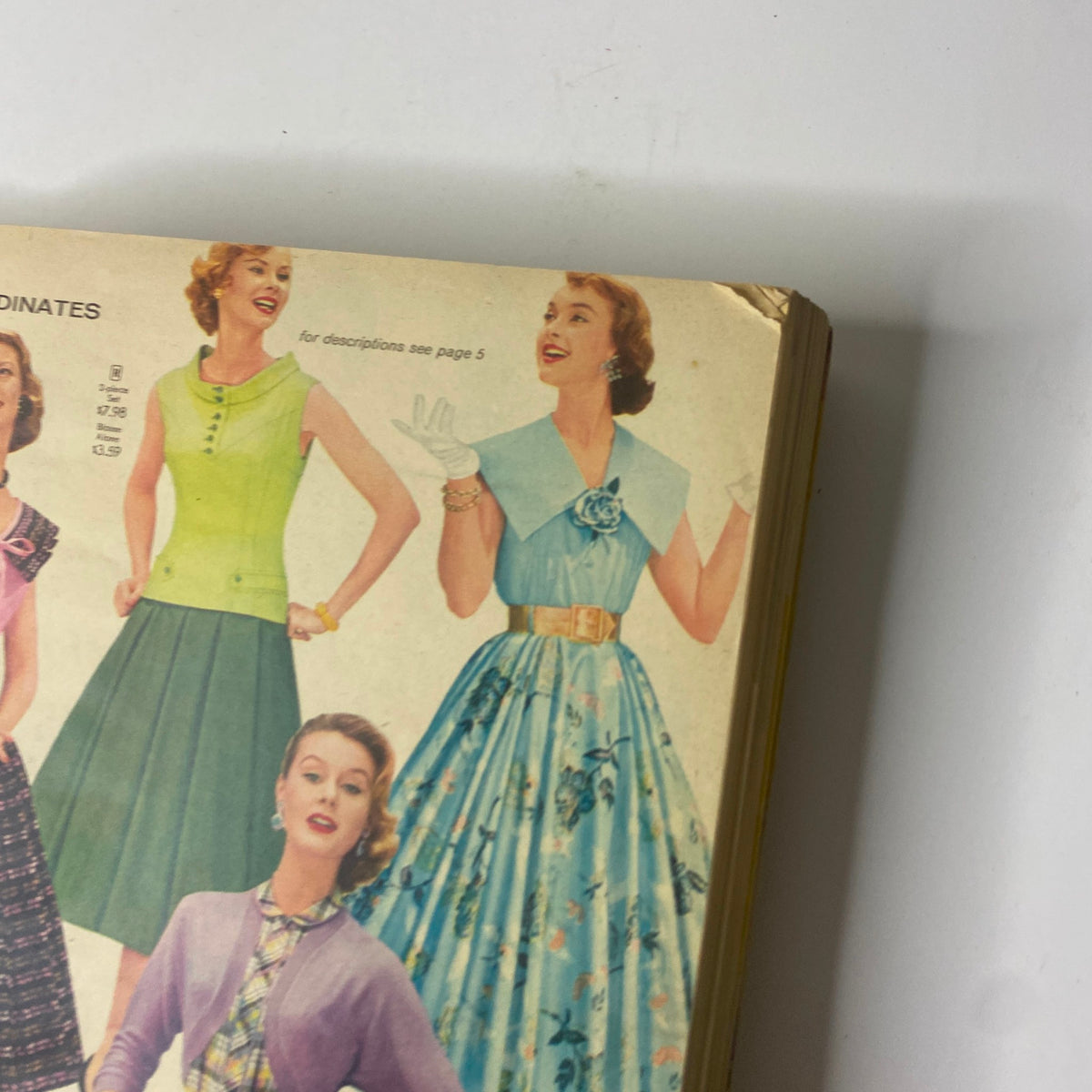 Close-up view of vintage dresses in the 1956 Sears Roebuck and Co. Spring and Summer Catalog, featuring colorful styles.