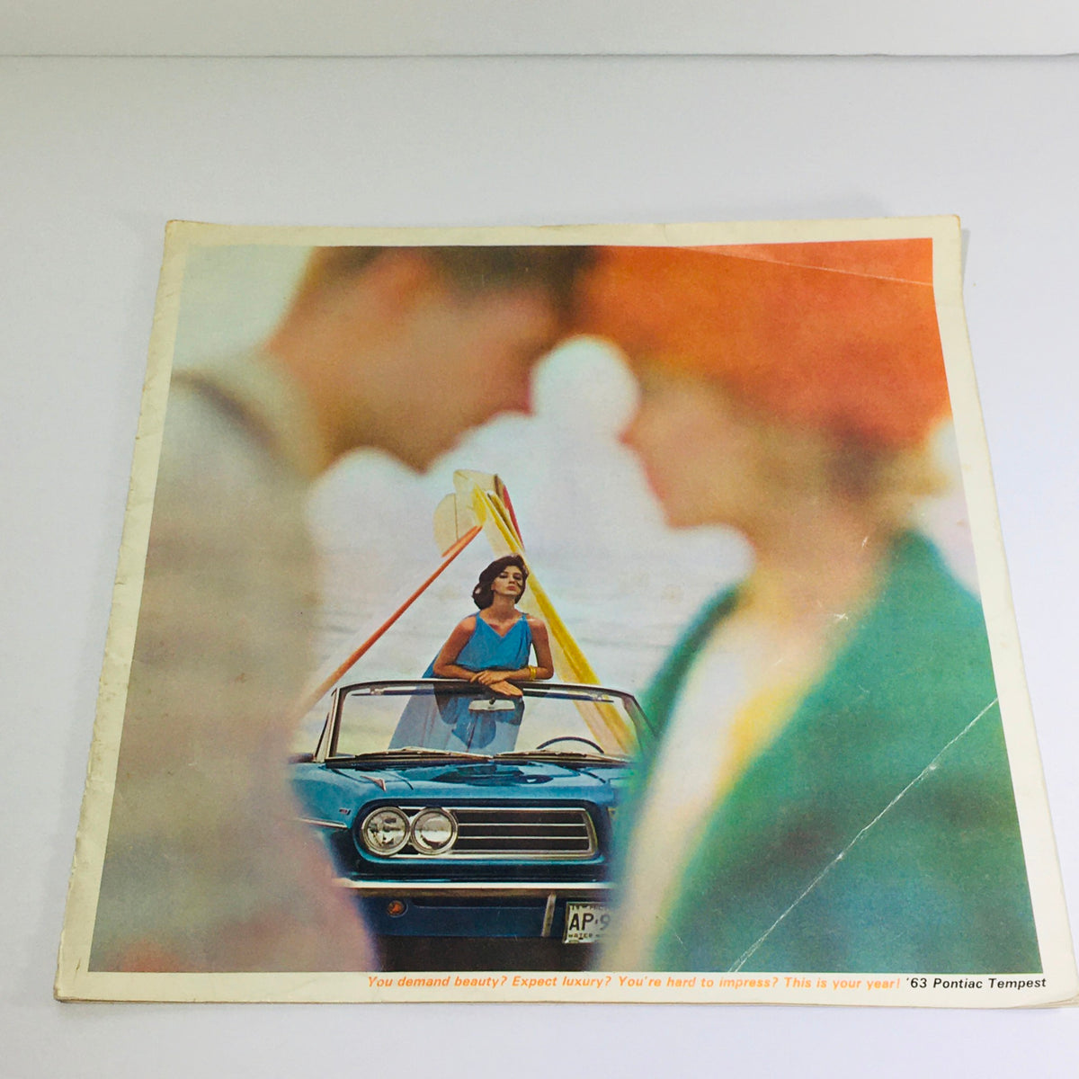 Cover image of a 1963 Pontiac Tempest showroom dealership brochure showcasing a classic blue Pontiac Tempest with a stylish woman and colorful surroundings.
