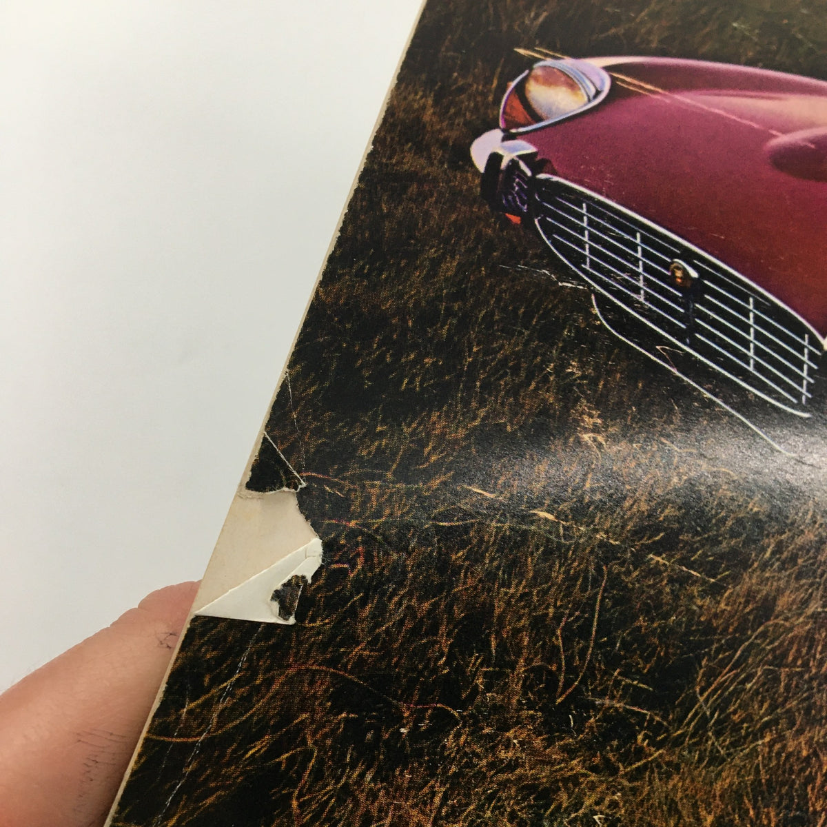 Close-up of a damaged corner of a page from Sports Car Magazine, April 1971, showing wear consistent with its vintage nature.