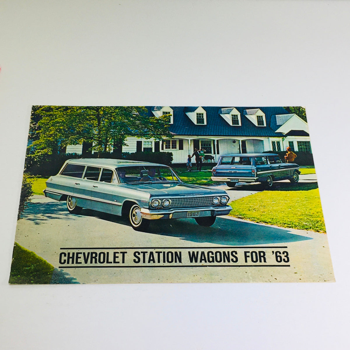 1963 Chevrolet Station Wagons Dealership Car Auto Brochure Catalog featuring classic station wagons in a suburban setting, showcasing vintage automobiles and 1960s architecture.