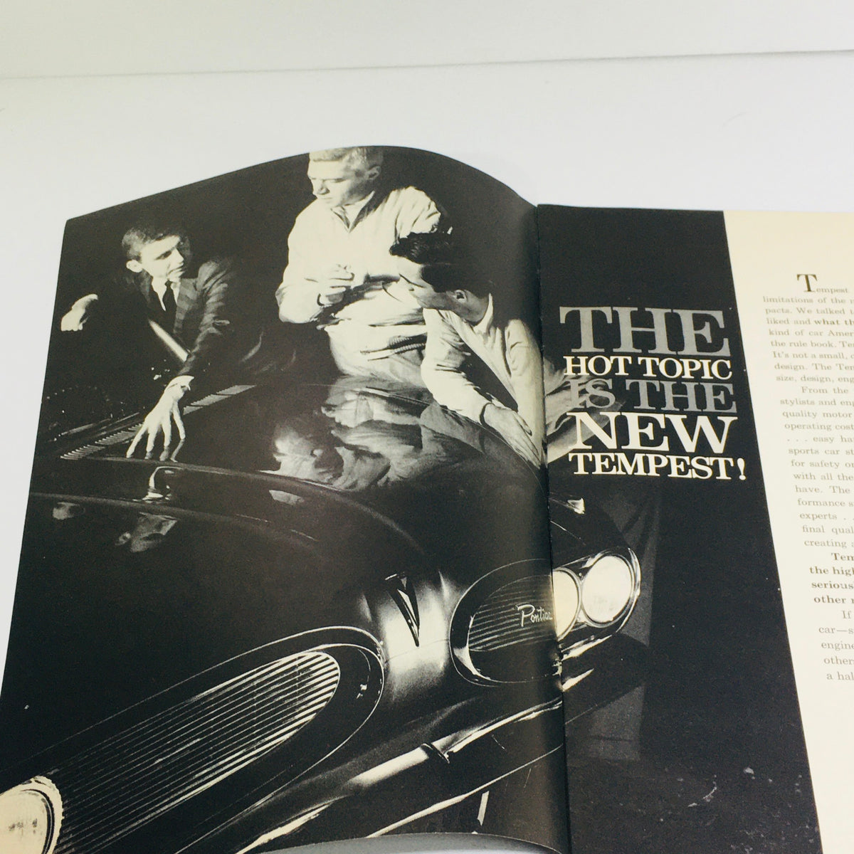 1961 Pontiac Tempest Showroom Dealership Car Auto Brochure Catalog featuring three individuals discussing the vehicle while leaning over its glossy surface.