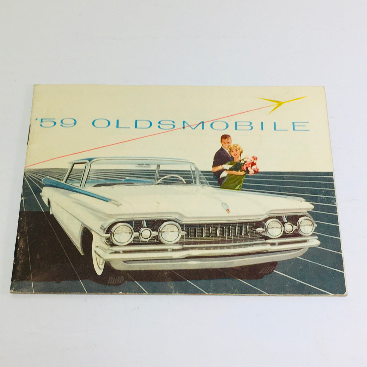 Cover of the 1959 Oldsmobile Holiday SceniCoupe Dealership Car Auto Brochure Catalog featuring a vintage car and a couple, showcasing classic automobile design.