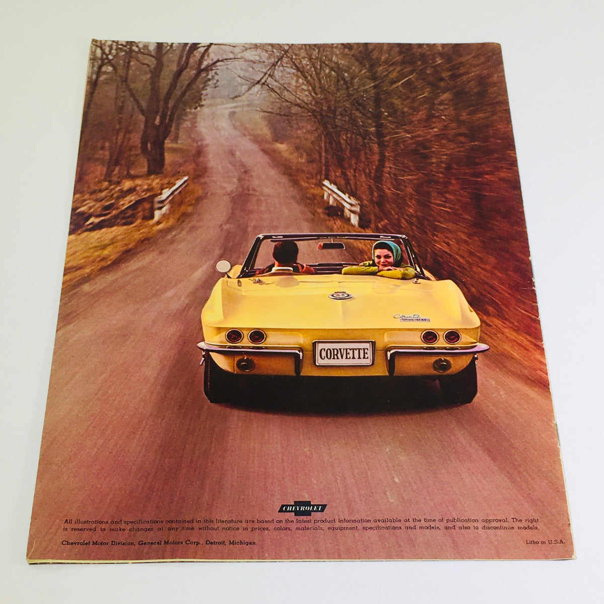 1965 Chevrolet Corvette Stingray Coupe brochure image with a yellow convertible on a rural road, highlighting the carefree driving experience.
