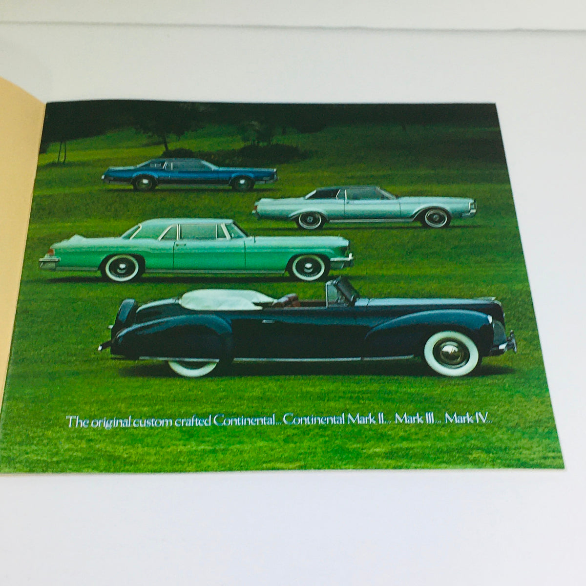 Inside page of the 1977 Continental Mark V Lincoln Continental brochure featuring classic cars displayed on a grassy field.