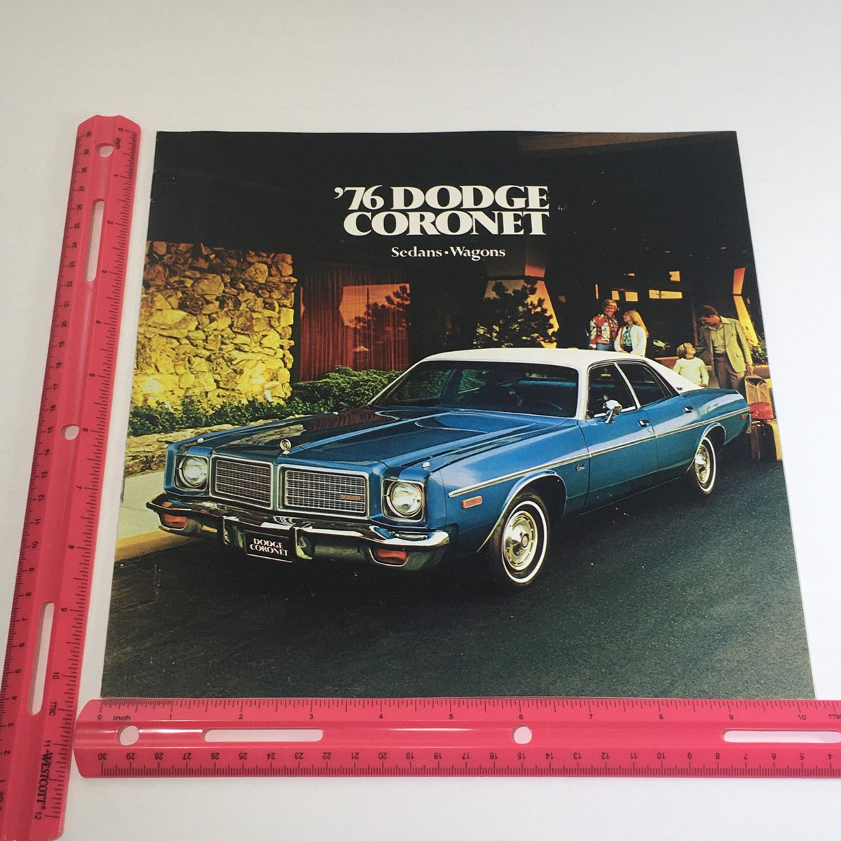1976 Dodge Coronet Sedans, Wagons Specifications Car Auto Brochure Catalog held next to a ruler for size reference, highlighting the cover design.
