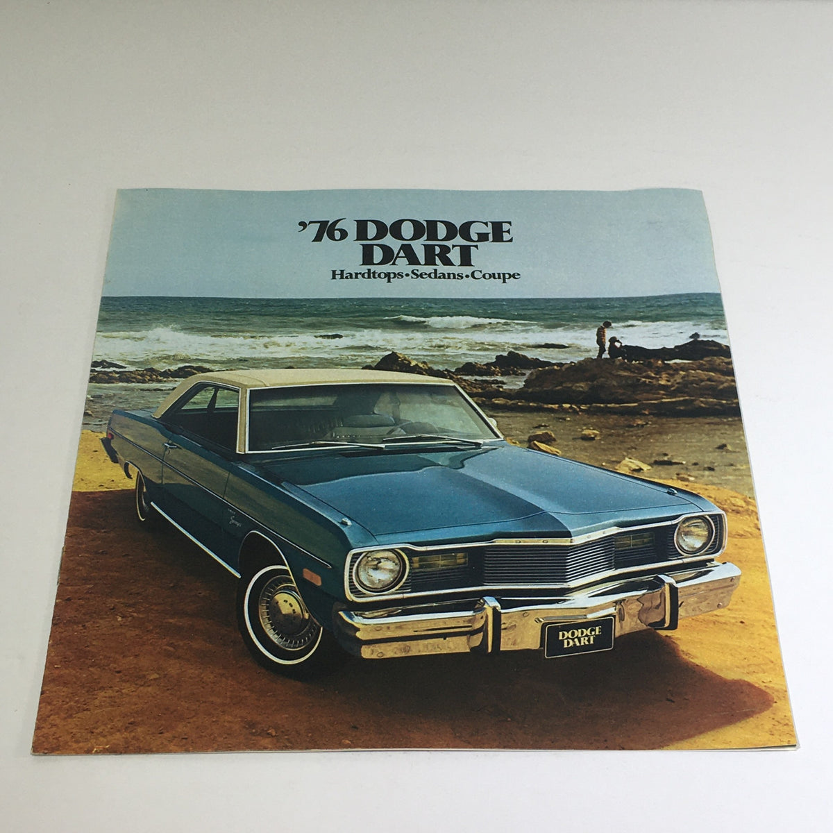 1976 Dodge Dart Hardtops, Sedans, Coupe Specifications Car Auto Brochure Catalog featuring a blue Dodge Dart parked on a beach with ocean waves in the background, showcasing its classic design and brochure cover.