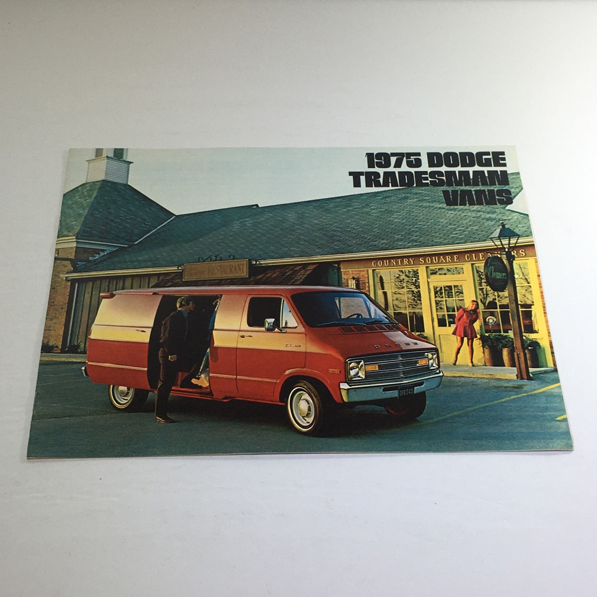 1975 Dodge Trucks Tradesman Vans Dealership Car Auto Brochure Catalog showing an orange Dodge Tradesman van parked outside a restaurant.