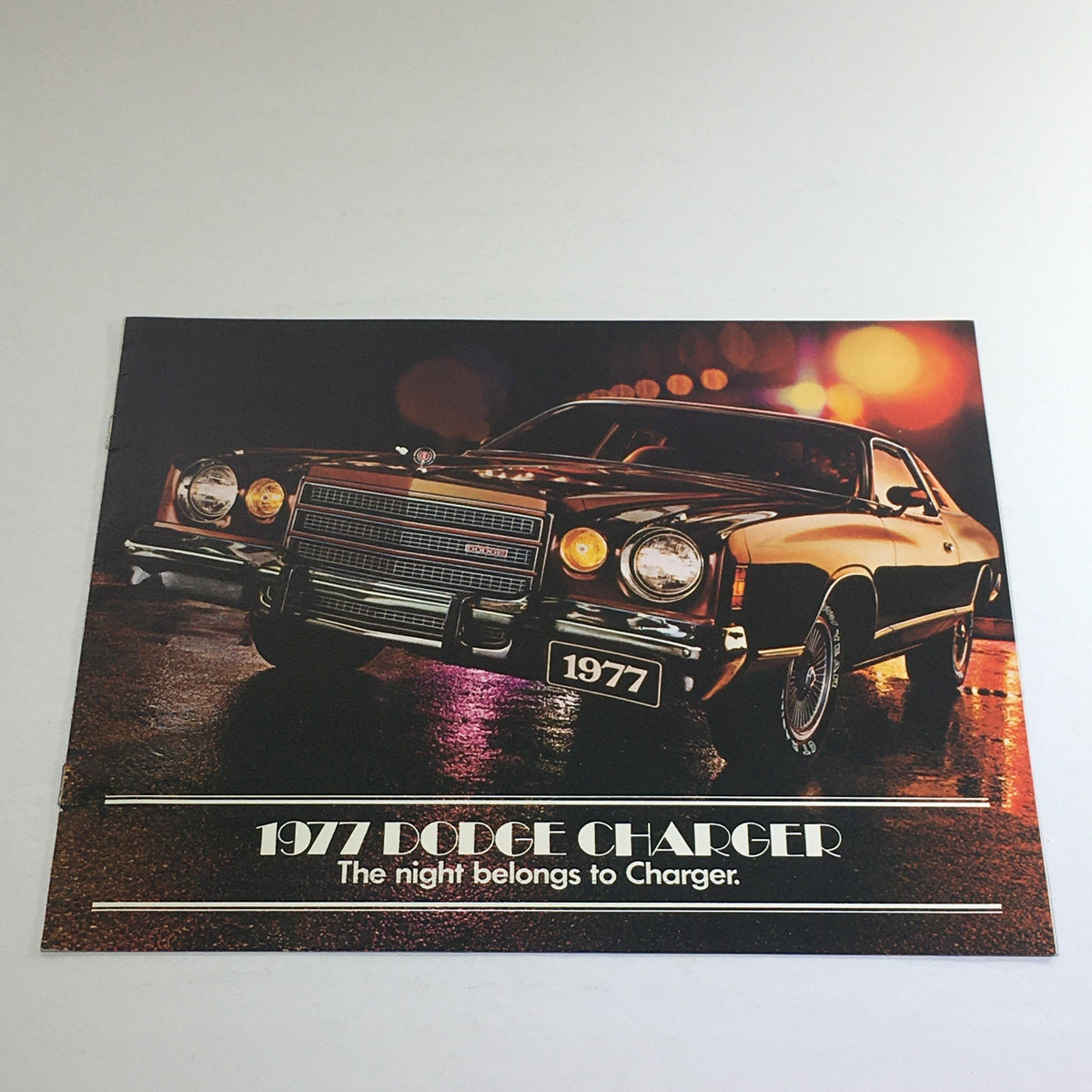 1977 Dodge Charger Specifications catalog showcasing the 1977 Dodge Charger automobile with unique frontal view illuminated in night setting, highlighting its stylish design and branding, suitable for car enthusiasts and collectors.