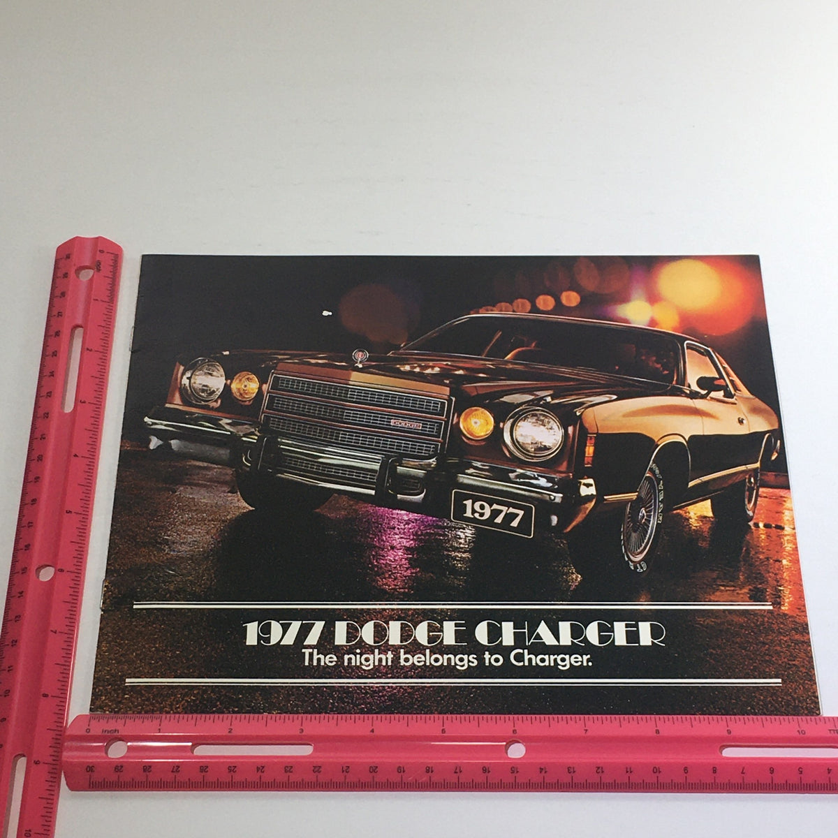 1977 Dodge Charger Specifications - Image of the 1977 Dodge Charger promotional material featuring a stylish black car under lights, showcasing the tagline 'The night belongs to Charger'.