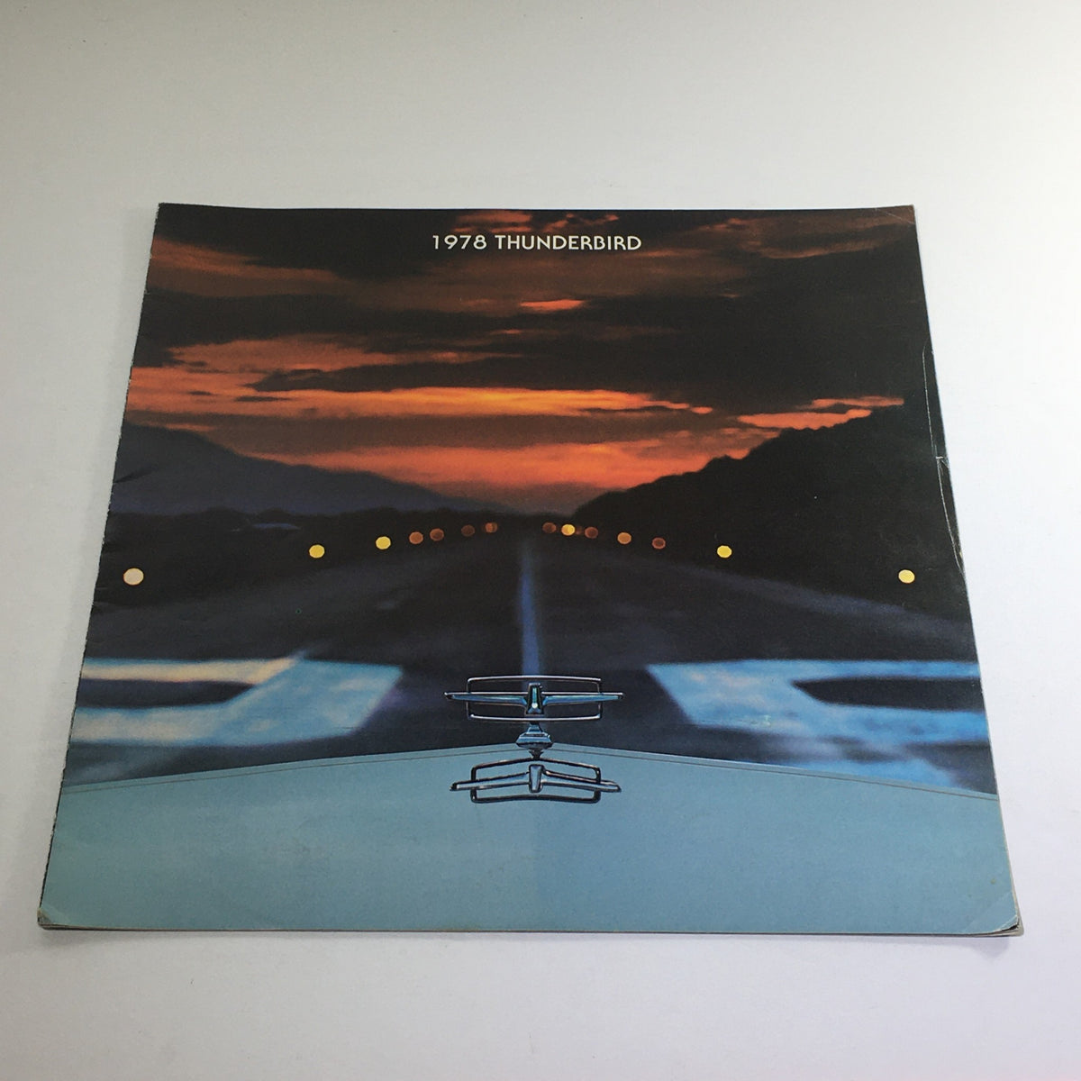 1978 Ford Thunderbird Town Landau Dealership Car Auto Brochure Catalog featuring a scenic view of a sunset over a highway with the car's hood ornament in the foreground.