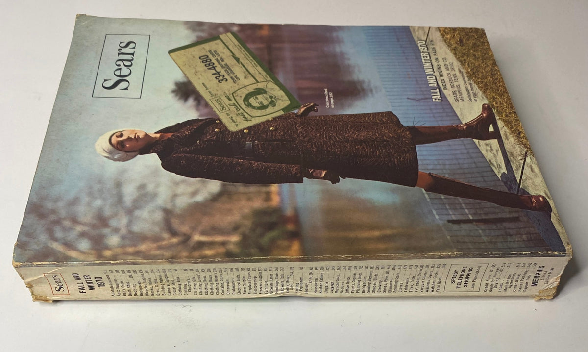 Side view of the 1970 Sears Roebuck and Co. Fall and Winter Catalog, displaying its spine and front cover with a model in a luxurious coat and a visible order form.
