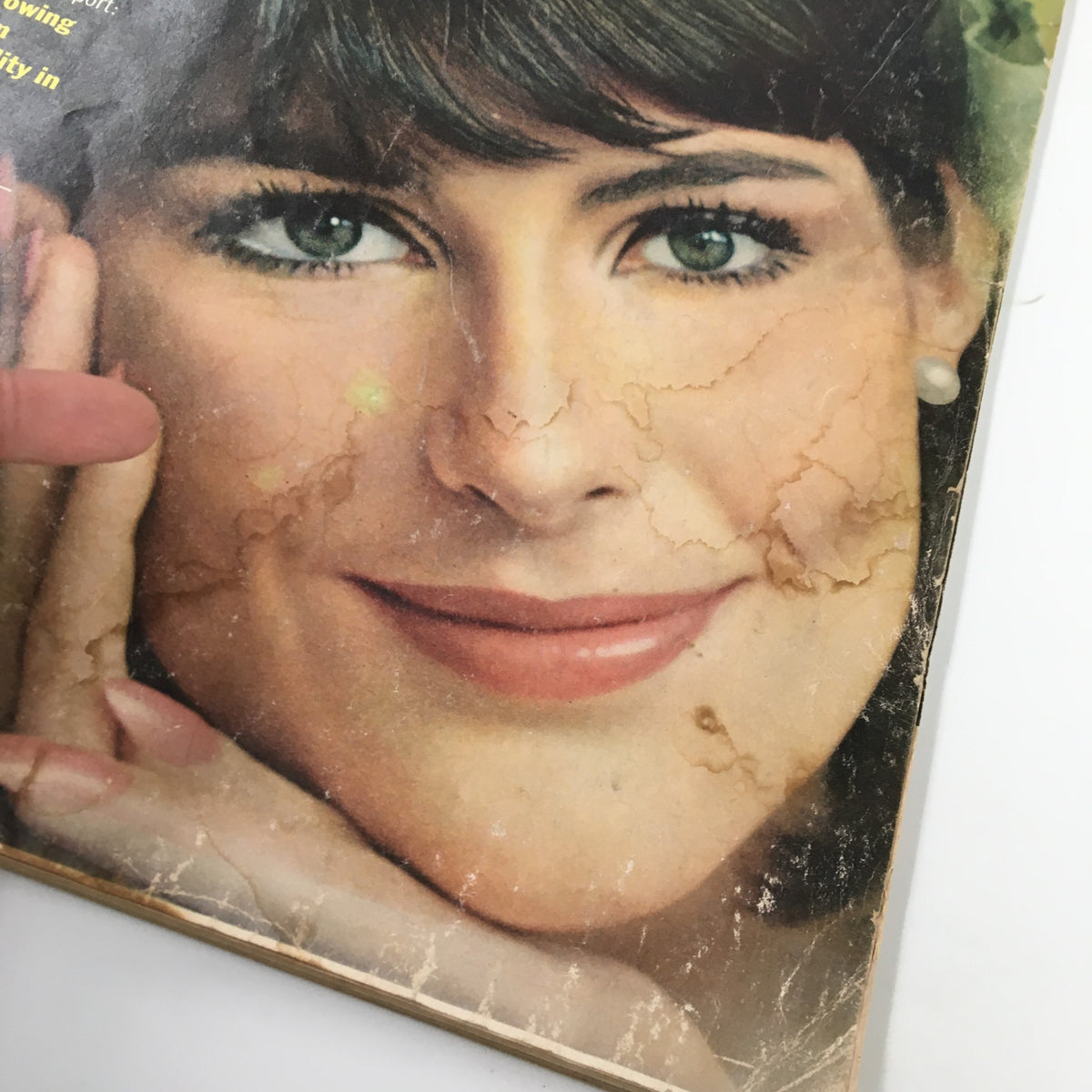 Close-up view of the cover of Ladies' Home Journal Magazine April 1965 featuring a vintage photograph of a smiling woman, Anne-Marie Barden, with visible signs of wear including scratches and discoloration.