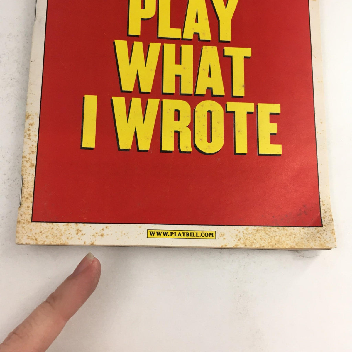 Close-up of the bottom corner of the 2003 Playbill for The Play What I Wrote, showing website details and signs of age on the cover.