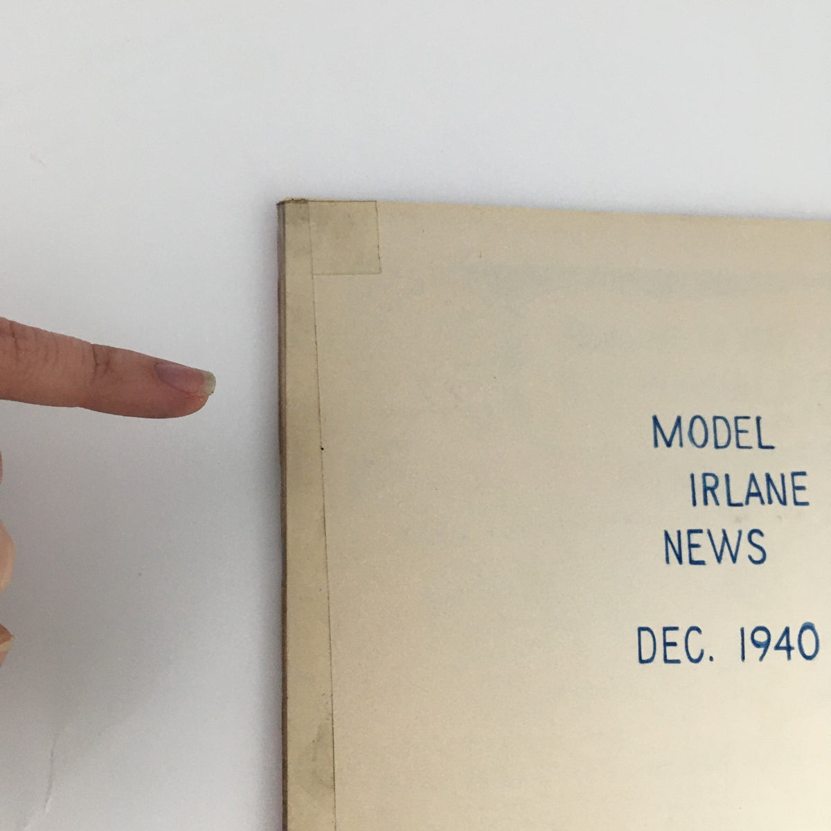 Detail of the backside of the December 1940 Model Airplane News Magazine, displaying the title 'MODEL IRLANE NEWS DEC. 1940' and signs of age, including a corner indicator and protective tape.