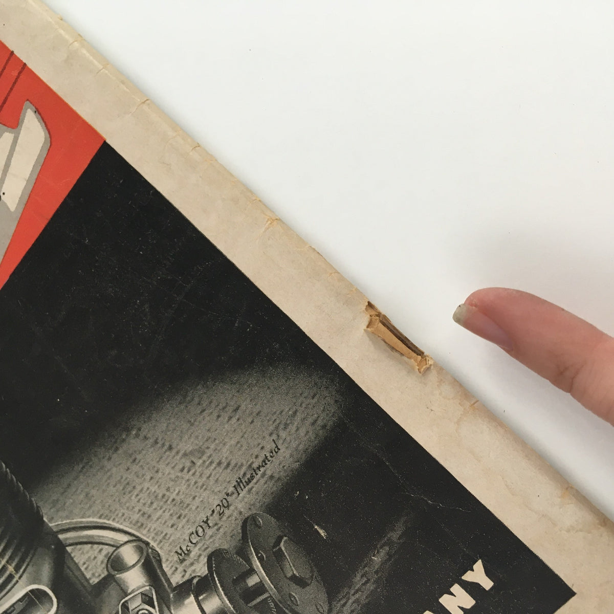 Detailed view of a tear on the cover of the Model Airplane News Magazine July 1950, illustrating the condition of this vintage item.
