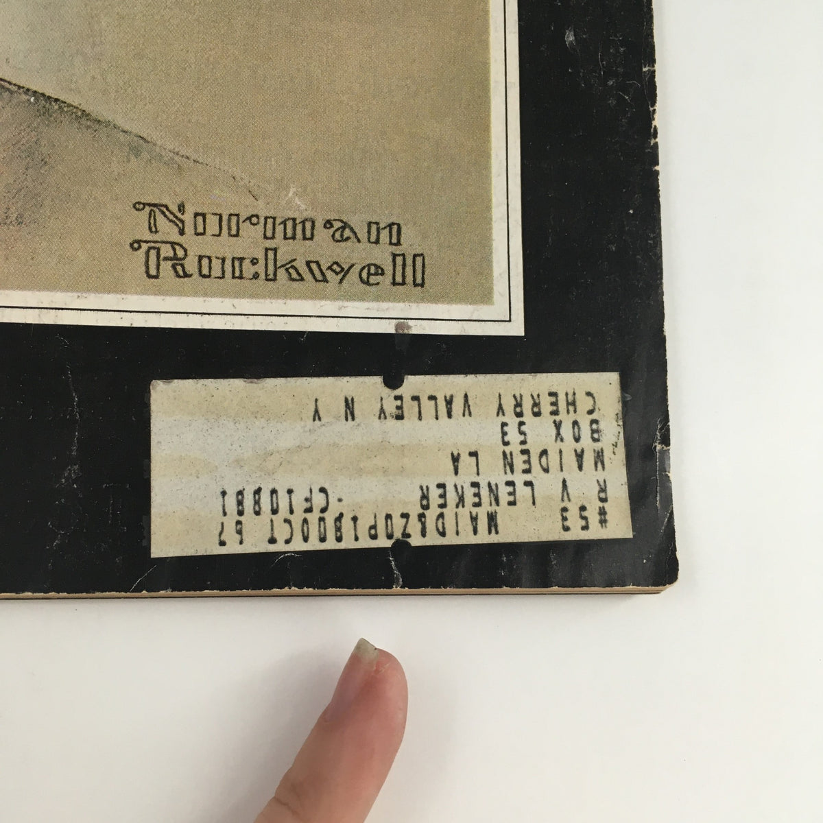 Close-up of the lower section of The Saturday Evening Post December 14 1963, showing the artist Norman Rockwell's signature along with an address label, encapsulating historical details of the magazine.