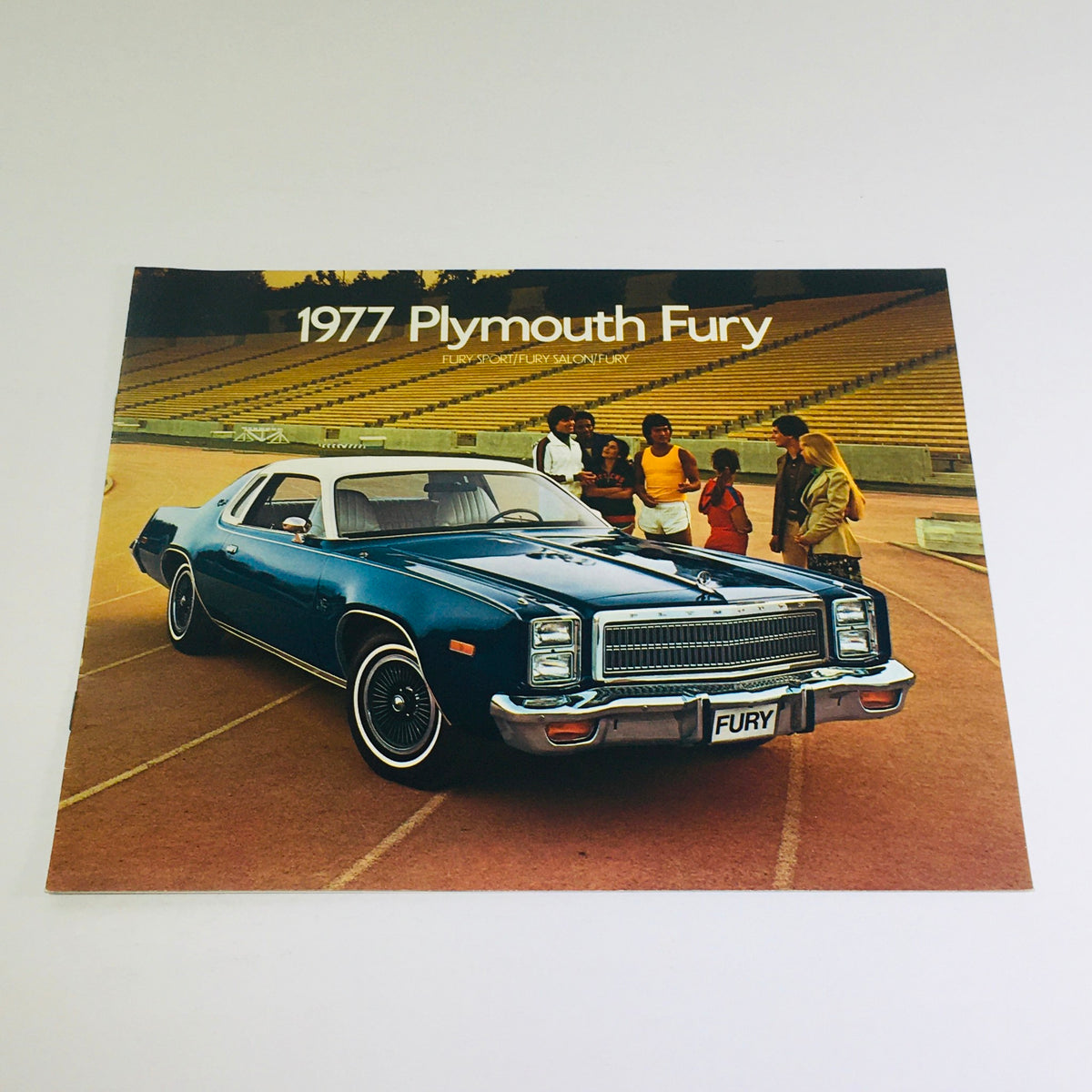 1977 Plymouth Fury Sport-Salon-Fury Dealership Car Auto Brochure showcasing a blue Plymouth Fury parked outdoors with a group of people in the background.