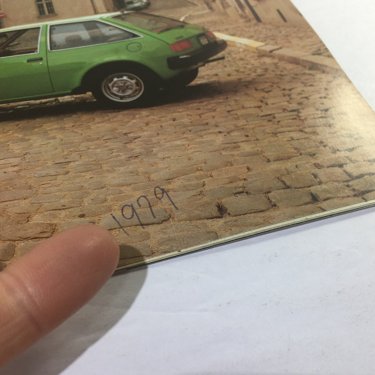 Close-up view of 1979 Chrysler-Mitsubishi Colt 2-Door/4-Door Dealership Car Auto Brochure Catalog showing a green car and the year '1979' in focus against a cobblestone backdrop.