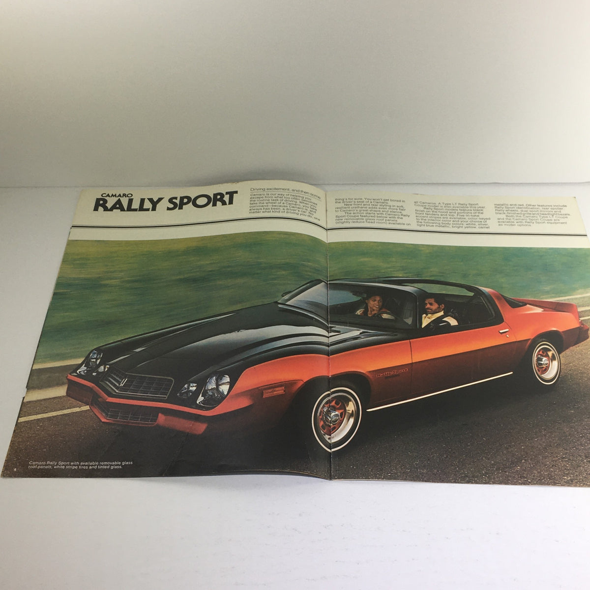 Inside view of the 1978 Chevrolet Camaro Rally Sport auto brochure showcasing a sleek black and red Camaro with two passengers.