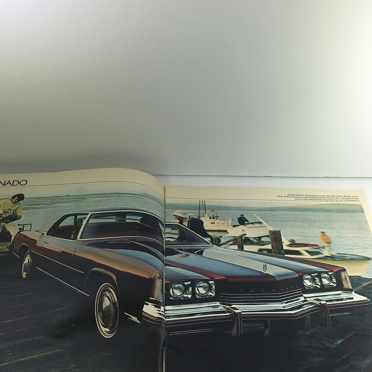 Interior page of the 1974 Oldsmobile Toronado-Ninety-Eight Dealership Car Auto Brochure Catalog showcasing a 1974 Oldsmobile Toronado parked by the water.