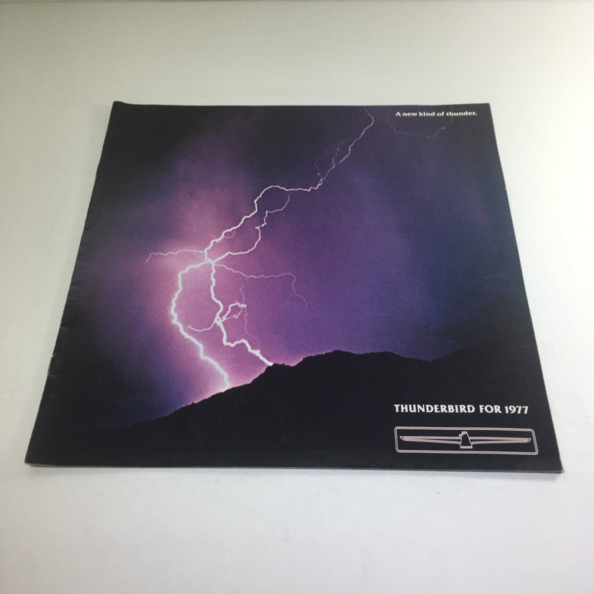 Cover of the 1977 Ford Thunderbird Deluxe Dealership Car Auto Brochure Catalog featuring a dramatic lightning storm illustration with the words 'A new kind of thunder.'