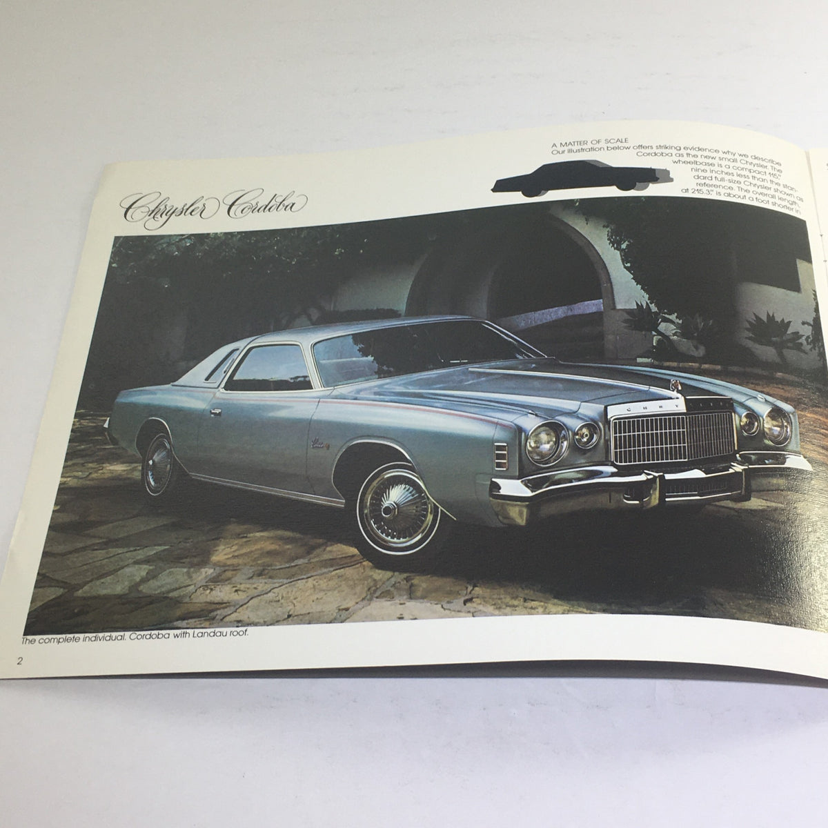 1975 Chrysler Cordoba Showroom Dealership Car Sale Auto Brochure Catalog displaying a silver Chrysler Cordoba with Landau roof, showcased in a picturesque setting.
