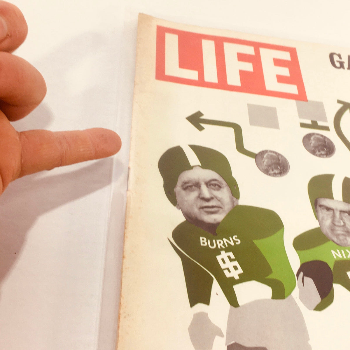 Close-up of the Vintage Life Magazine cover from August 27, 1971, showing detailed illustrations of football players labeled Burns and Nixon, with a finger pointing at the cover, emphasizing the magazine's 'Game Plan For The Dollar' theme.