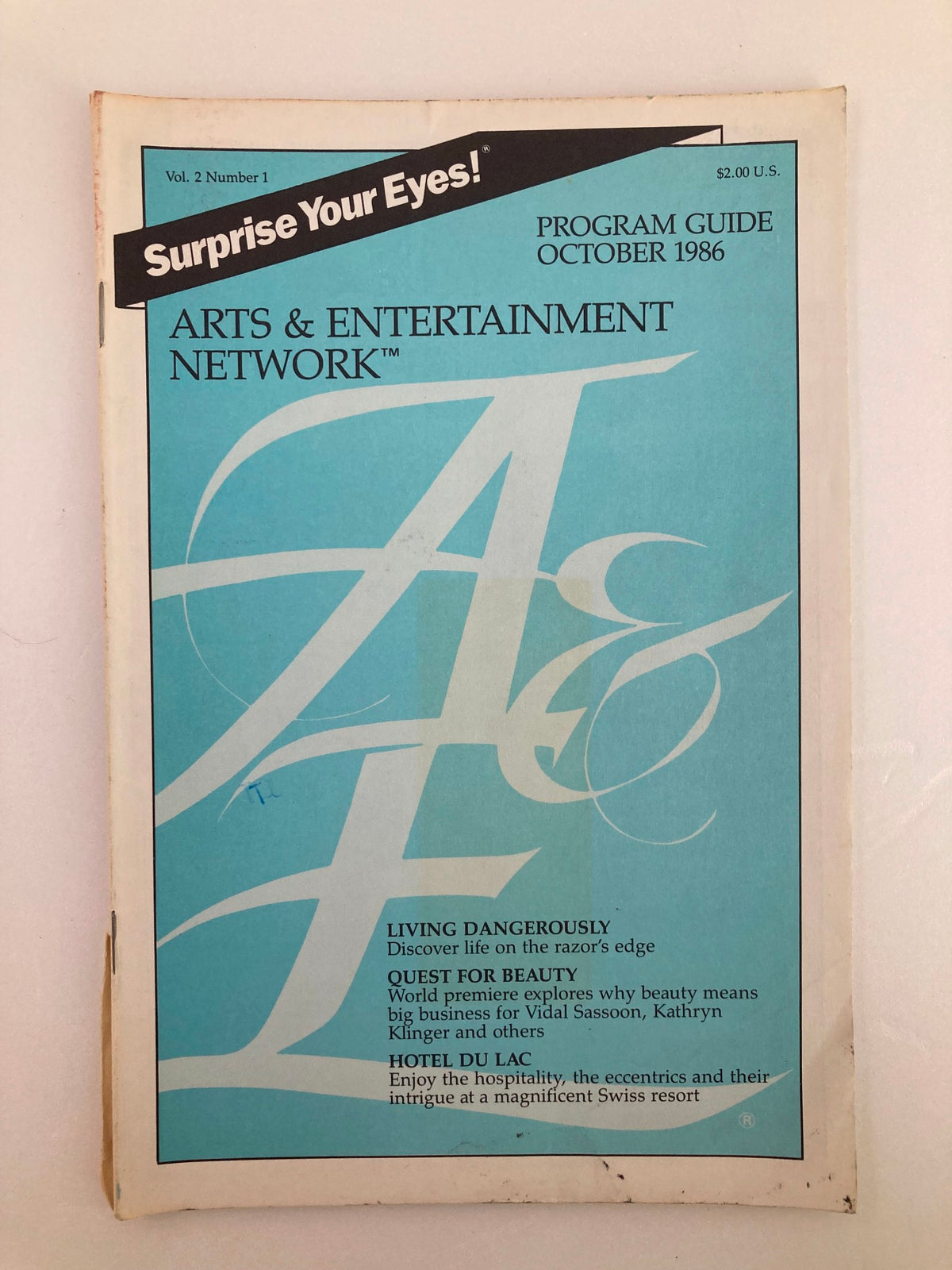 Cover of the A&E Cable Network Program Guide for October 1986, Volume 2 Number 1, titled 'Living Dangerously', featuring the show's title and network branding in a vibrant blue design.
