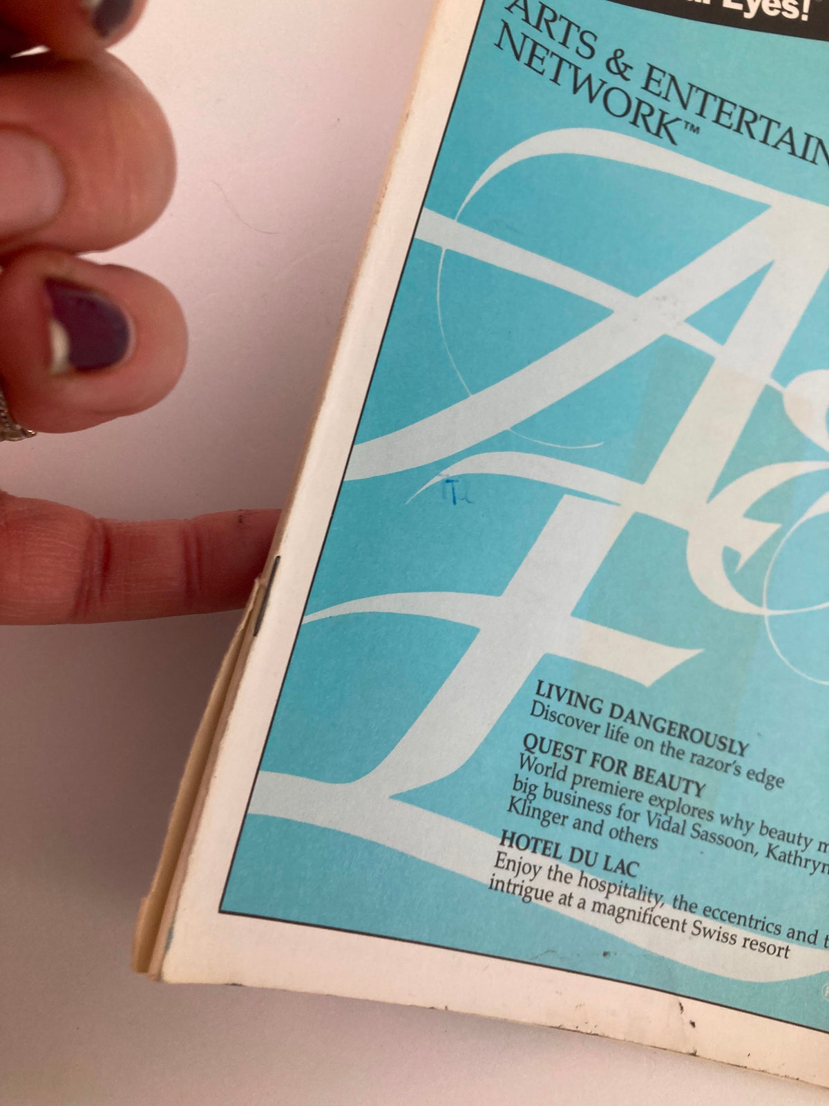 Close-up view of the edge of the A&E Cable Network Program Guide for October 1986, displaying the title 'Living Dangerously' and details about featured shows.