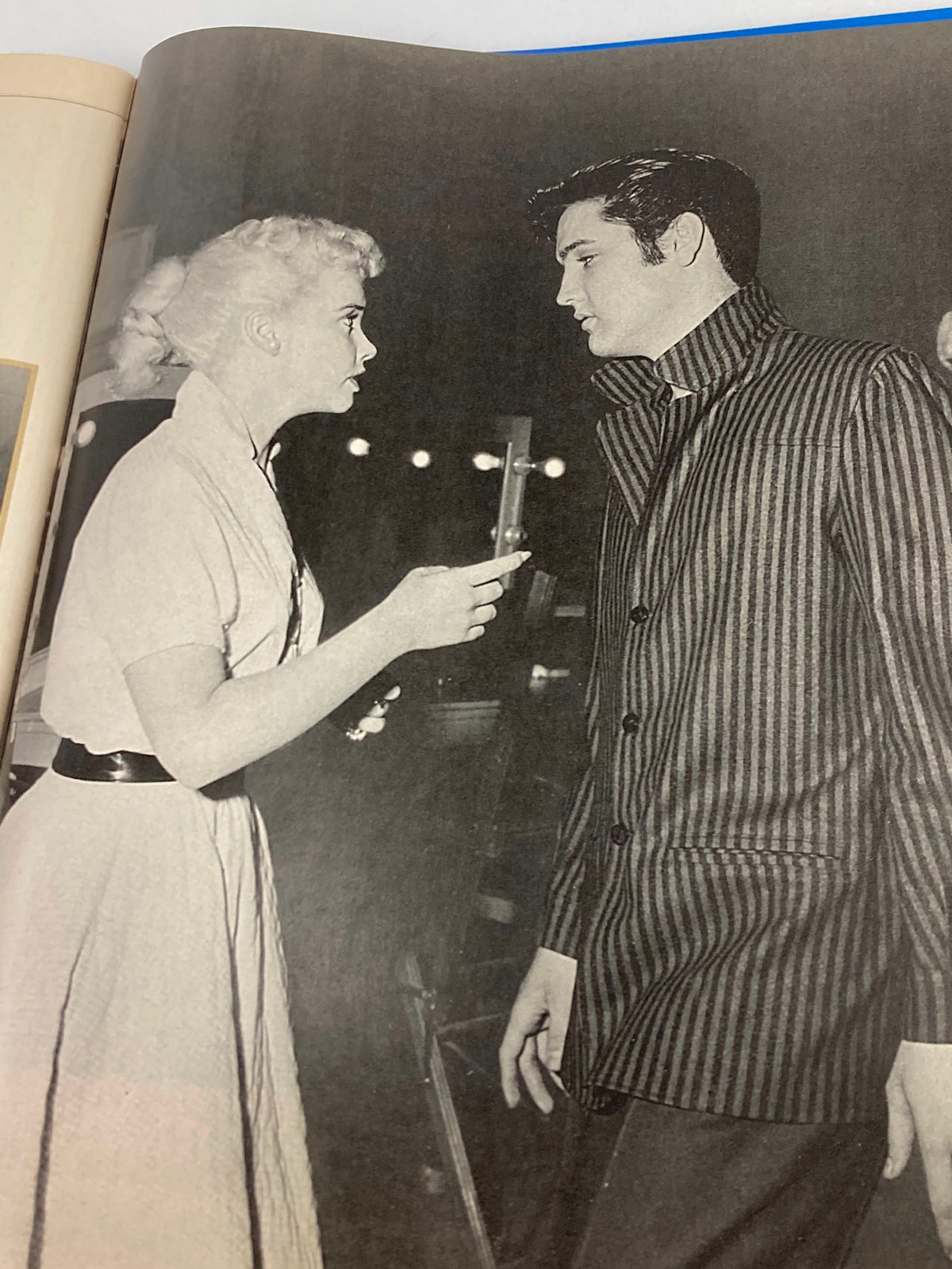 Image from VTG Remembering Elvis Magazine 2002 featuring Elvis Presley in a striped jacket engaging in conversation, showcasing a moment from his iconic early years.