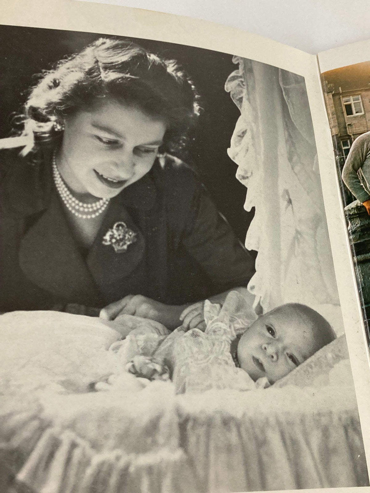 Black and white photograph from the VTG Royal Family Souvenir 1973 Picture Book, showing a young Queen Elizabeth II looking affectionately at a baby.