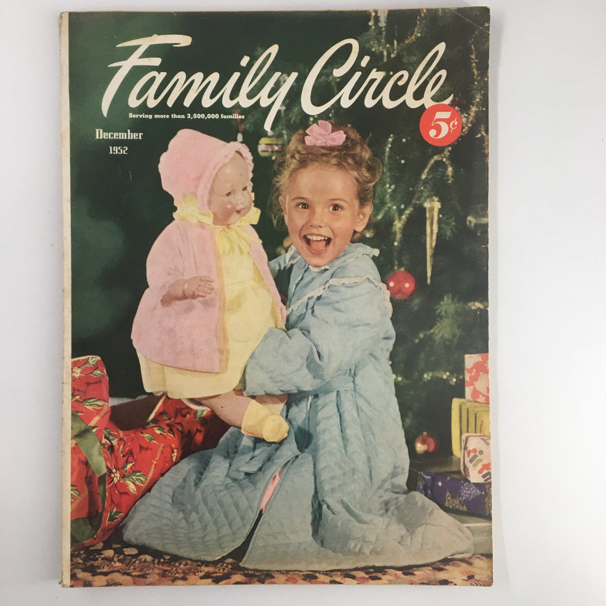 Cover of VTG Family Circle Magazine from December 1952 featuring a cheerful girl holding a doll, surrounded by Christmas decorations. This issue focuses on 'Minute Main Dishes for Holiday,' showcasing vintage recipes perfect for festive occasions.