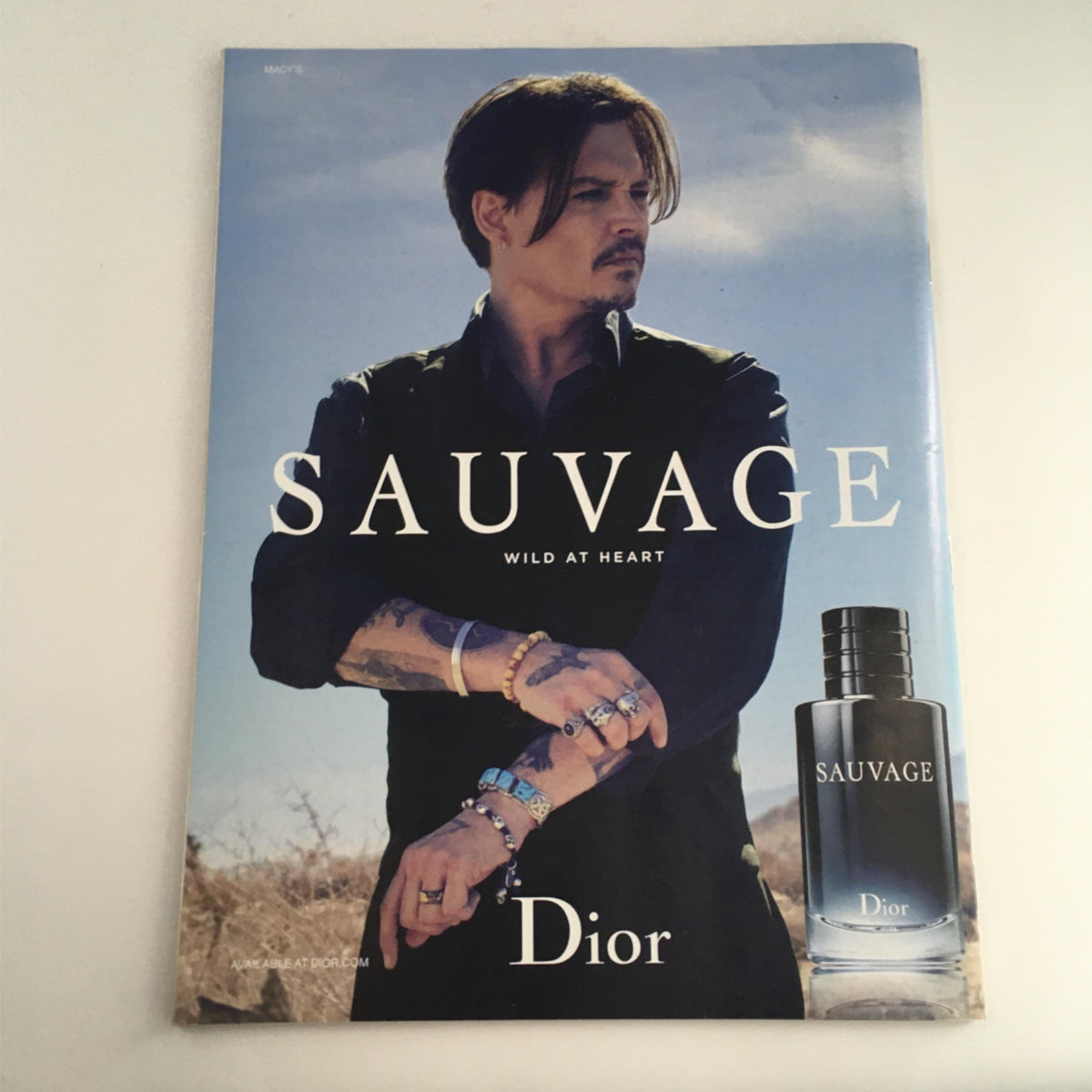 Dior Sauvage advertisement featuring a male model with a modern hairstyle and accessories, promoting the fragrance 'Wild at Heart'.