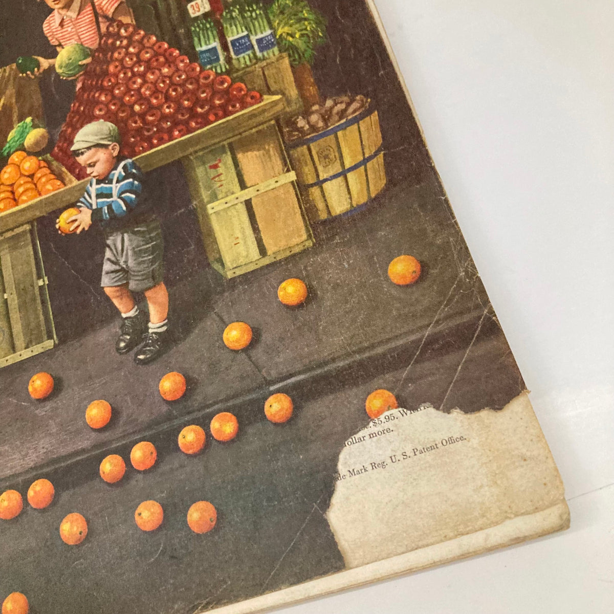 Detailed view of the bottom portion of the cover of the Saturday Evening Post Magazine from September 19, 1953, showcasing a young boy with an orange among fallen oranges, set against a backdrop of a bustling market.