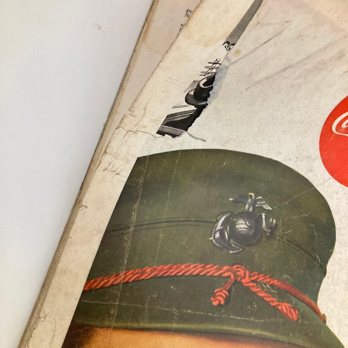 Close-up of a Coca-Cola advertisement from February 21 1953, in Saturday Evening Post Magazine, showing a woman's military cap with a logo and damaged edge, emphasizing vintage design details.
