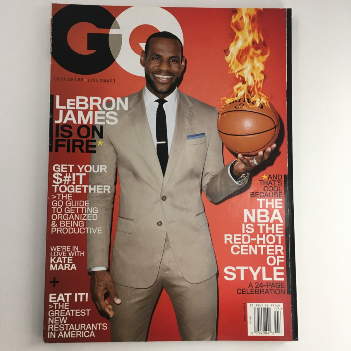 GQ Magazine March 2014 cover featuring LeBron James in a suit holding a basketball with flames, titled 'LeBron James Is On Fire'. This vintage magazine showcases the intersection of sports and style.