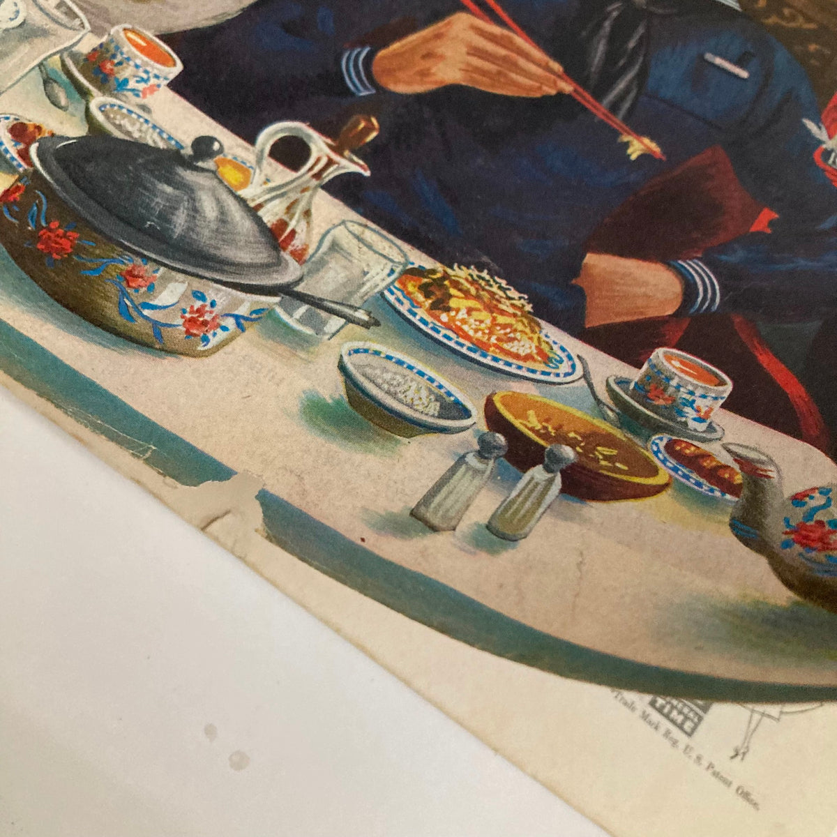 Close-up view of the dining table from Saturday Evening Post Magazine January 12, 1952 showcasing a variety of dishes, chopsticks, and elegant tableware from the 'Chopstickers' cover artwork by Alajalov.