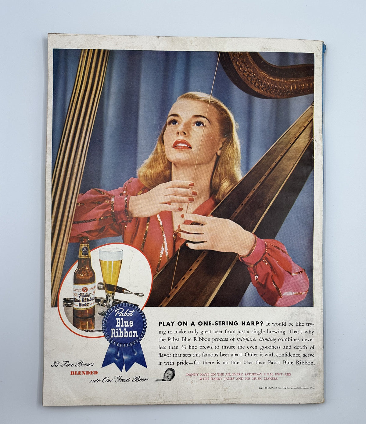Esquire Magazine March 1945 advertisement for Pabst Blue Ribbon beer featuring a glamorous woman playing a one-string harp, promoting the drink with a vintage aesthetic.