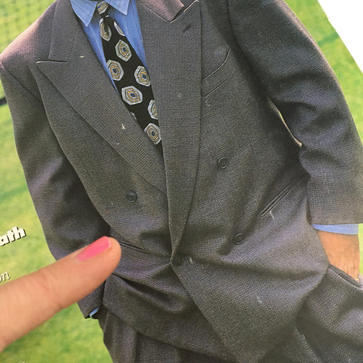 Detailed portrait of a stylishly dressed figure in a gray suit with a patterned tie from GQ Magazine September 1989 featuring Andre Agassi, Dean Stockwell, and Brian DePalma. The figure's hand is visible, pointing at the suit's pocket, emphasizing the fashion of the era.