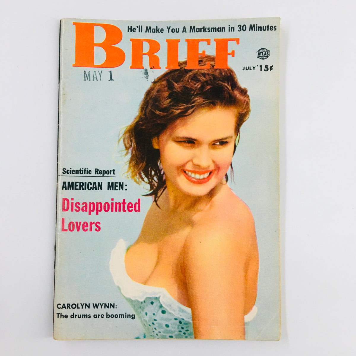 VTG Brief Magazine July 1956 cover featuring a smiling woman in a blue dress; the title reads 'The Drums are Booming' by Carolyn Wynn.