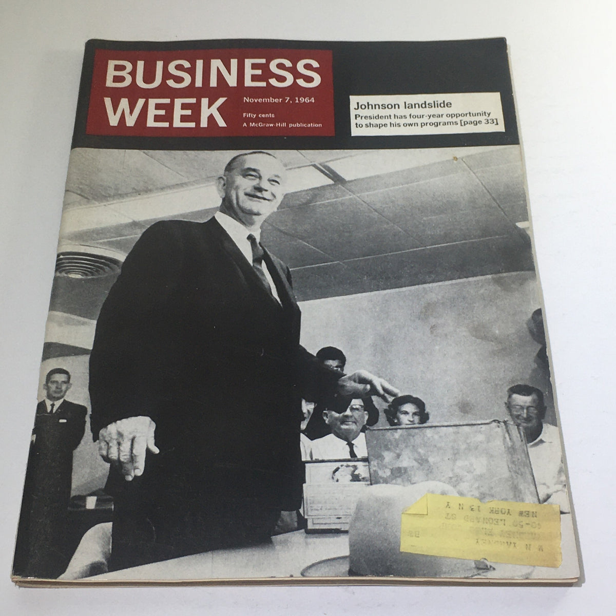 Business Week Magazine from November 7, 1964, featuring an iconic cover displaying the headline 'Johnson Landslide'. The image includes a prominent figure standing in an office setting, surrounded by attentive onlookers, providing a glimpse into the political atmosphere following President Lyndon B. Johnson's significant electoral victory.