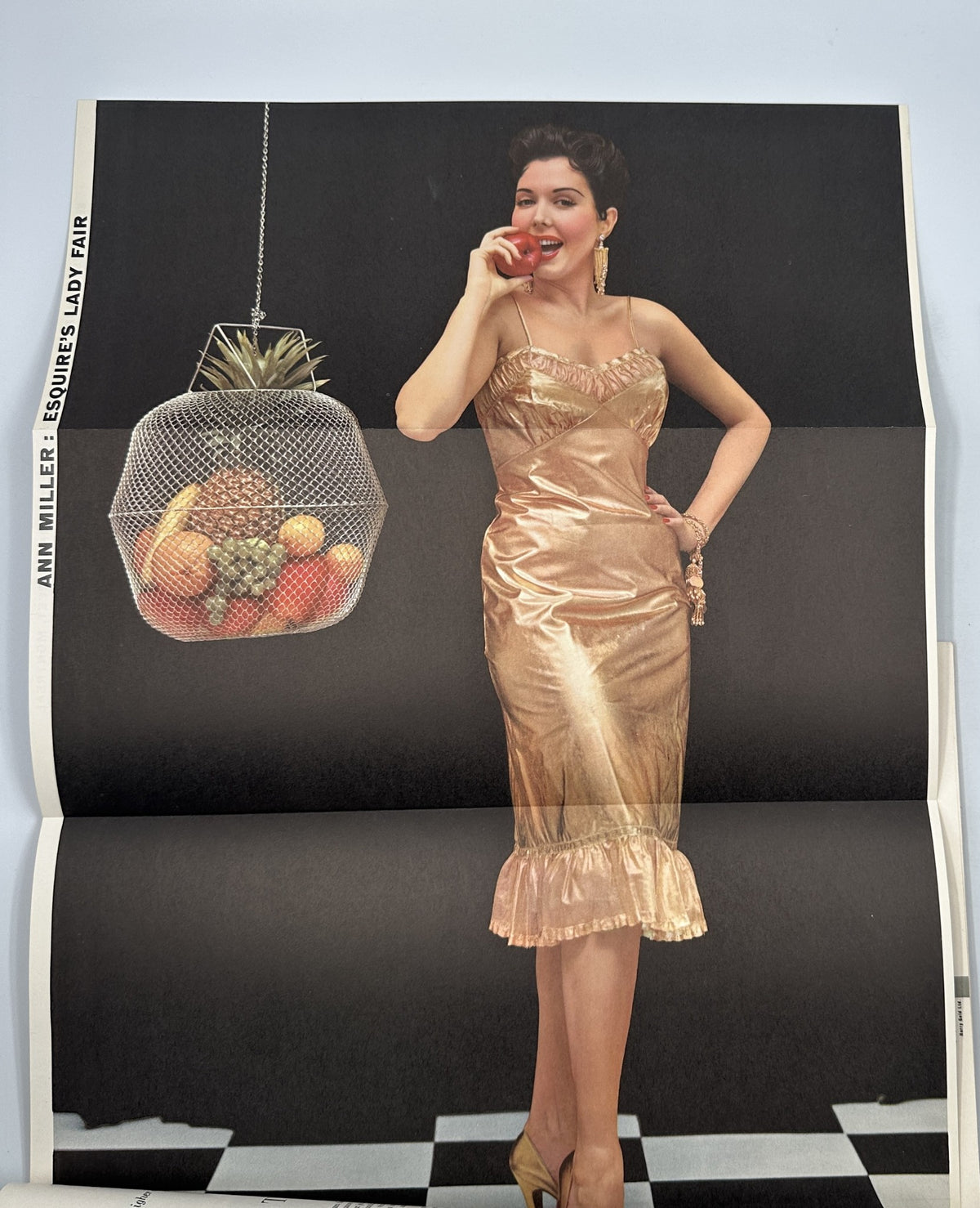 Ann Miller featured in Esquire Magazine May 1954, posing elegantly with an apple, showcasing vintage fashion and photography.