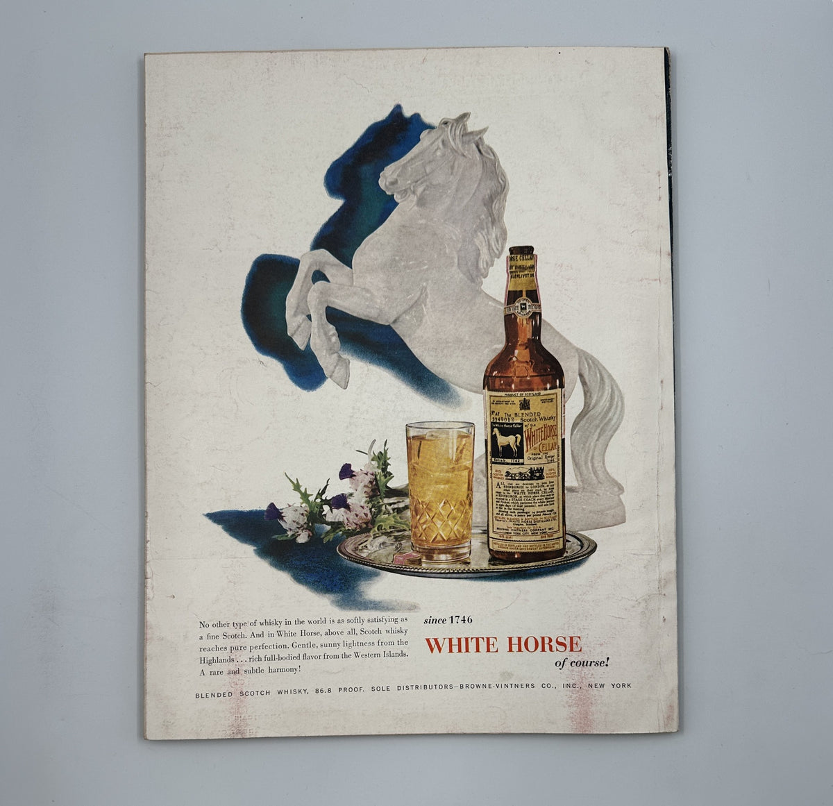 Esquire Magazine April 1955 back cover showcasing a White Horse whiskey advertisement featuring a horse silhouette and a glass of whiskey, highlighting mid-century advertising aesthetics.